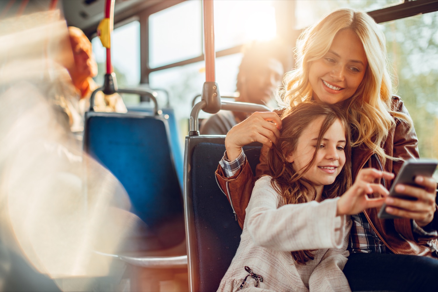 Close up of a mother and daughter using a phone in a bus